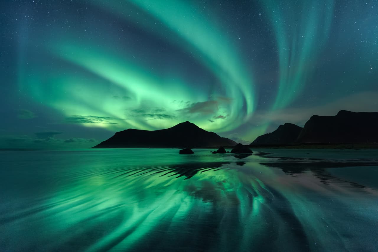 Reflejos. Las ondas de la aurora boreal se ven reflejadas en las olas que se producen en la marea baja de la playa Skagsanden en Alemania.