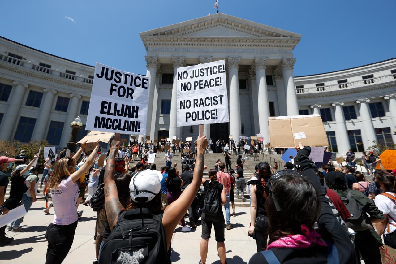 Participantes agitan pancartas durante una protesta afuera del ayuntamiento de Denver, Colorado, por la muerte de
<a href="https://www.univision.com/noticias/estados-unidos/acusan-de-asesinato-al-expolicia-que-sometio-violentamente-a-george-floyd-y-le-causo-la-muerte">George Floyd</a>.
