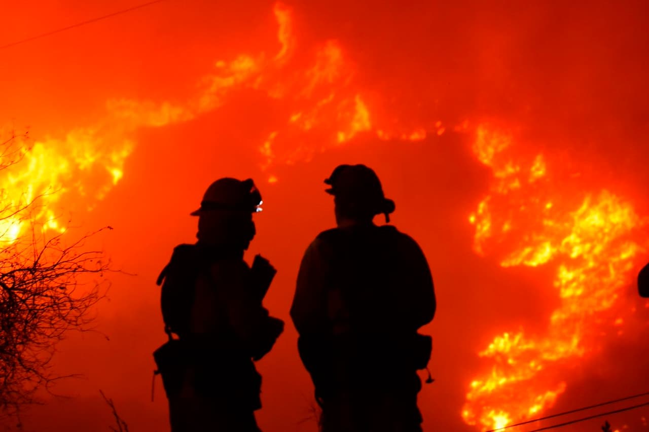 Bomberos del Condado de Santa Bárbara trabajan en la protección de estructuras del fuego Thomas mientras observan de cerca las llamas en la cima de Shepard Mesa Road, en Carpinteria, California.