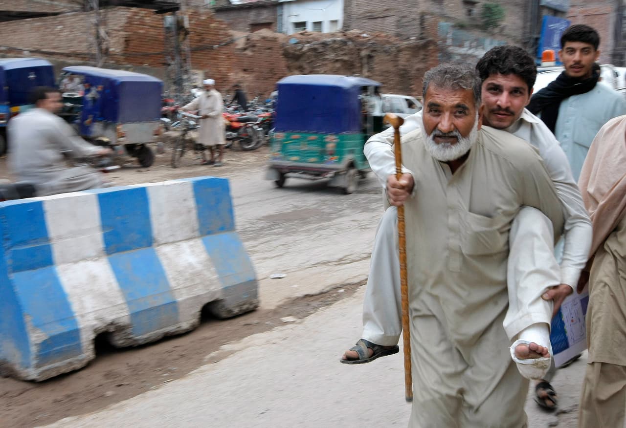 Un hombre lleva a un herido por las calles de Peshawar (Pakistán).