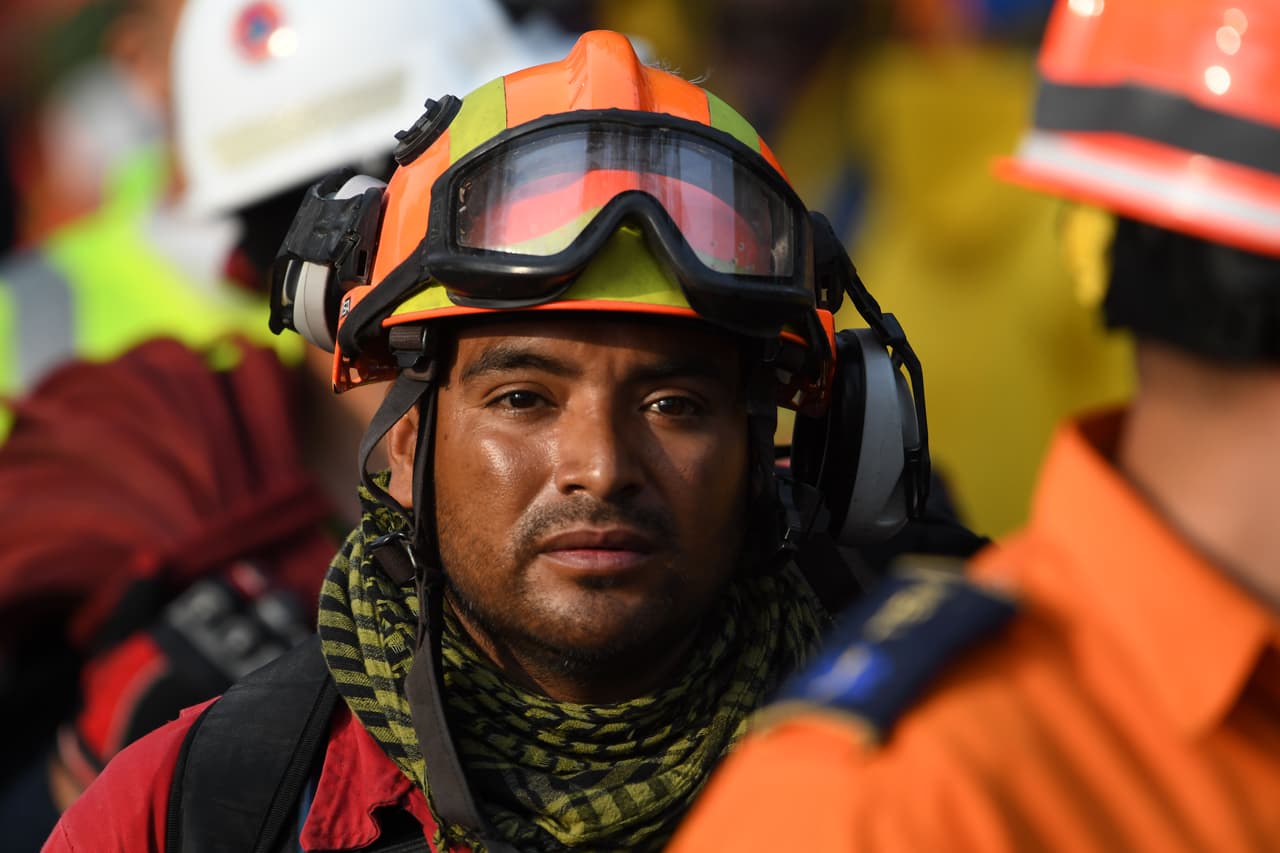 La luz de la tarde que se cuela a través de los edificios de la Ciudad de México ilumina el rostro preocupado de este rescatista.