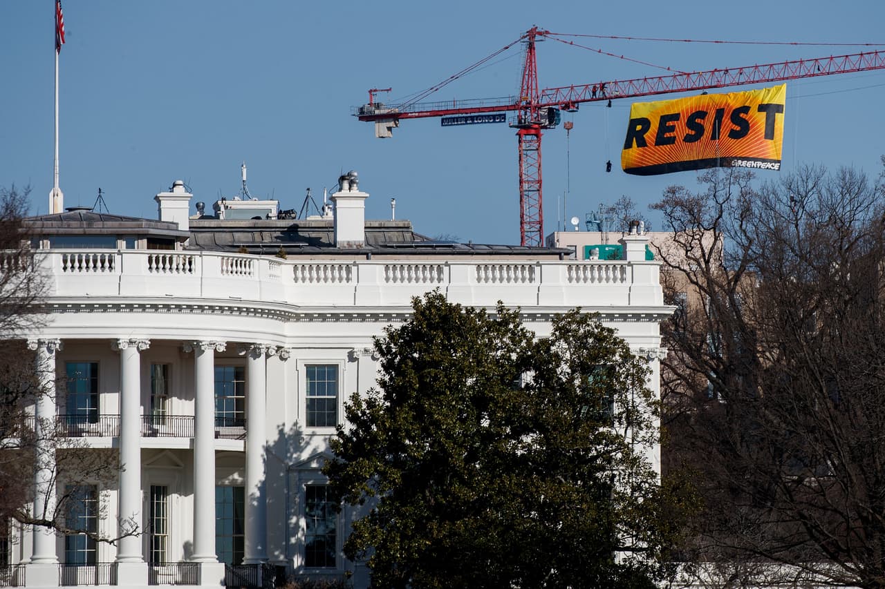 WASHINGTON, DC - JANUARY 25: With the White House in the foreground, protesters unfurl a banner atop a crane at the construction site of the former Washington Post office building, January 25, 2017 in Washington, DC. The protestors are with the Greenpeace organization. (Photo by Drew Angerer/Getty Images)