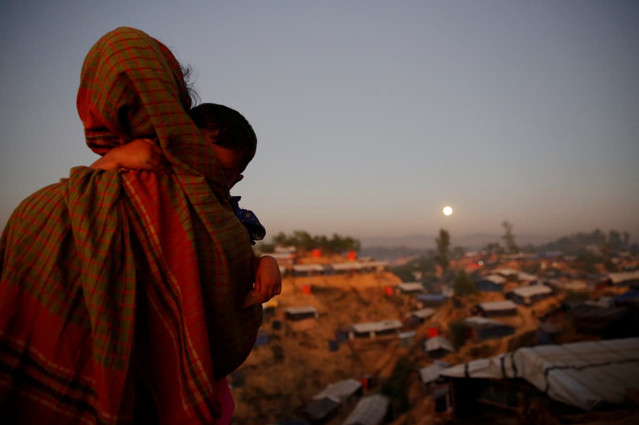 Una refugiada de la etnia rohingya con su pequeño hijo en brazos contempla la superluna desde un campo de refugiados en Balukhali, Bangladesh.