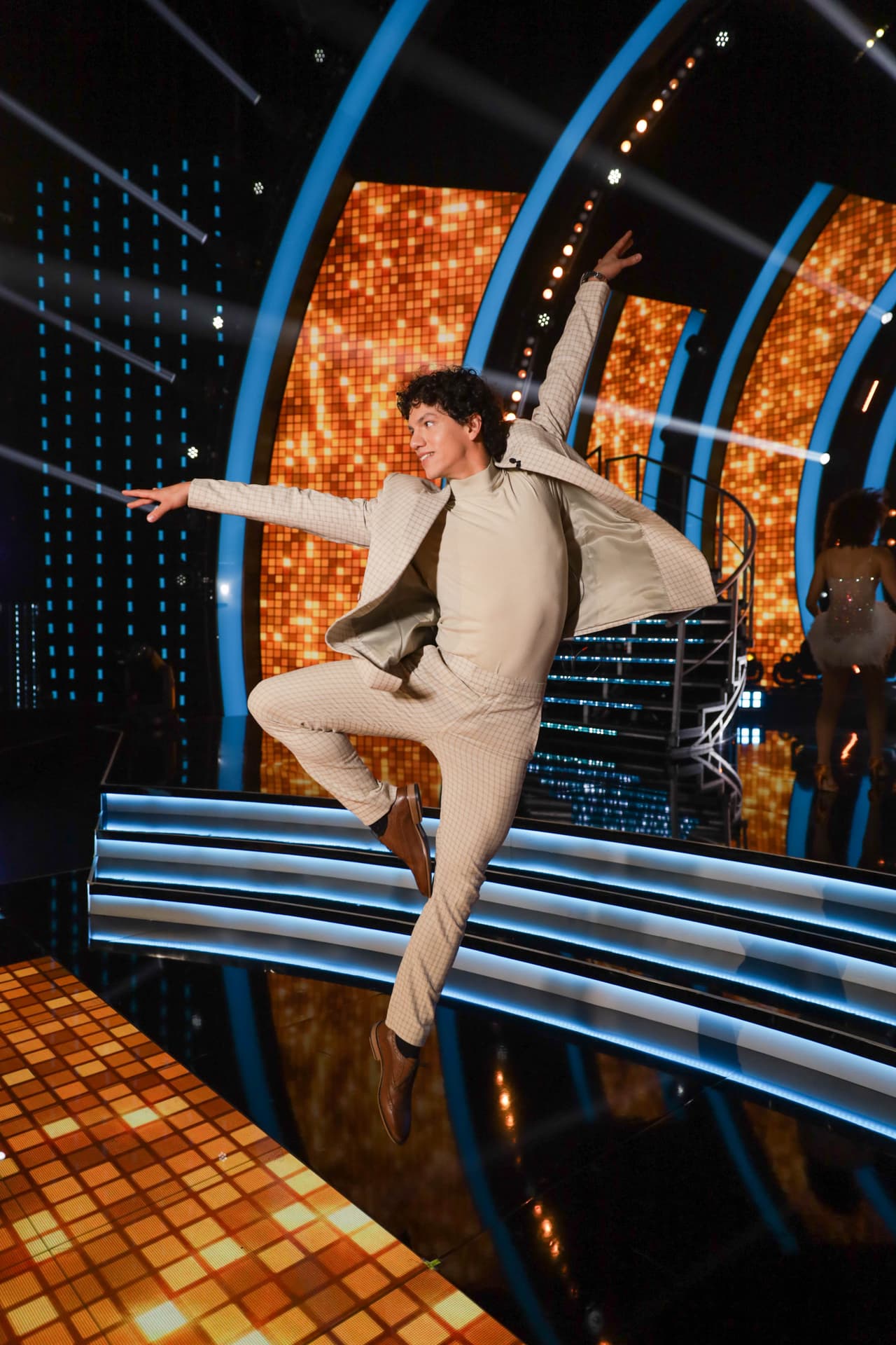 Su traje estaba decorado con una fina cuadrícula arena, la cual combinaba a la perfección con sus zapatos cafés de piel.