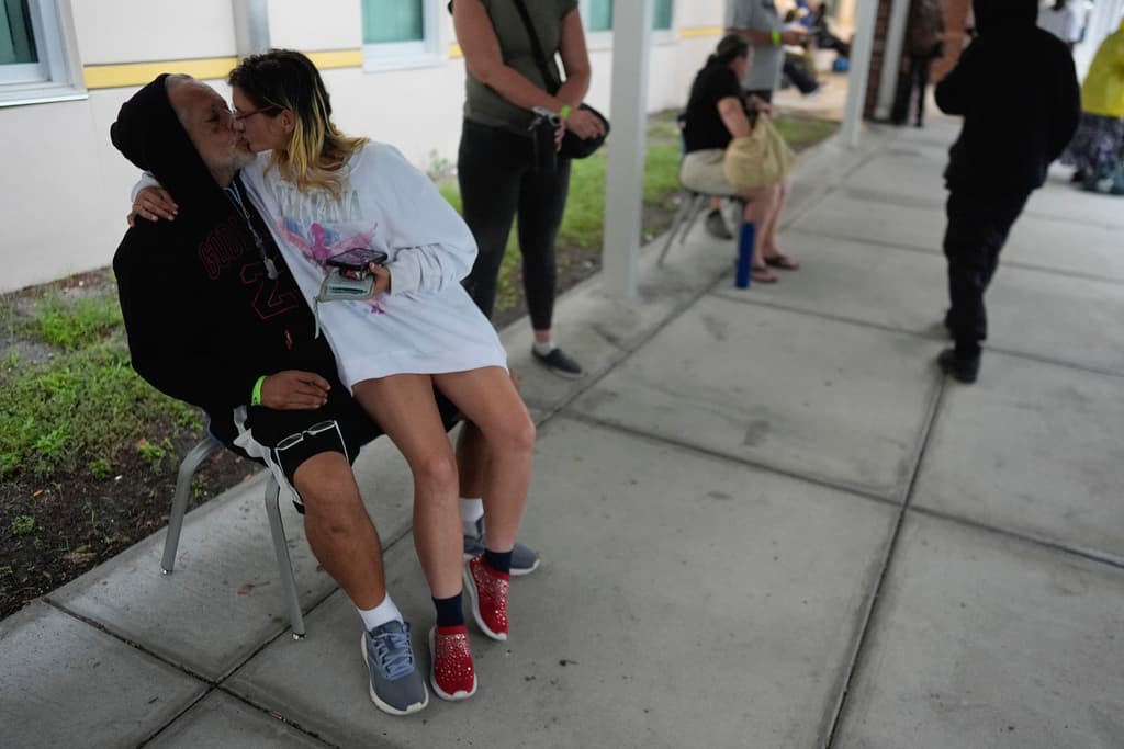 <b>Se dan tiempo para el amor a persar del mal tiempo: </b>John Biscaino, de 61 años, y su prometida Heather Lawhead, de 38, que no tienen hogar, se besan mientras pasan el tiempo afuera de un refugio del gobierno al que se mudaron por seguridad antes de la llegada del huracán Milton que ahora azota Florida, el miércoles 9 de octubre de 2024, en la escuela secundaria Gibbs en St. Petersburg, Florida. La pareja, que se conoció en un refugio para personas sin hogar a principios de este año, espera recibir pronto asistencia del gobierno para mudarse a una casa rodante. (Foto AP/Rebecca Blackwell)