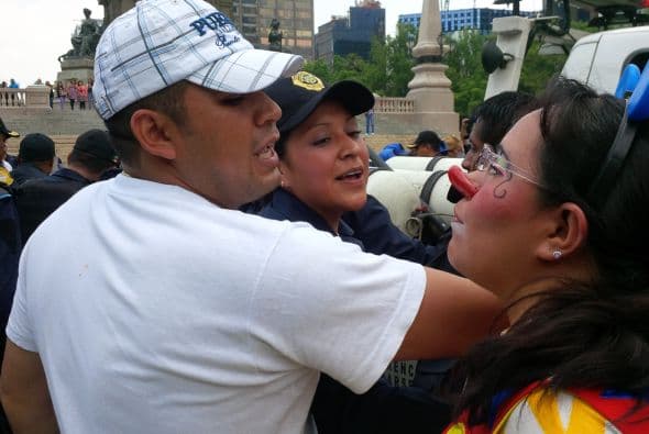 Una mujer y una niña vestidas de payaso le increpan, luego de que una uniformada jalara a la menor.