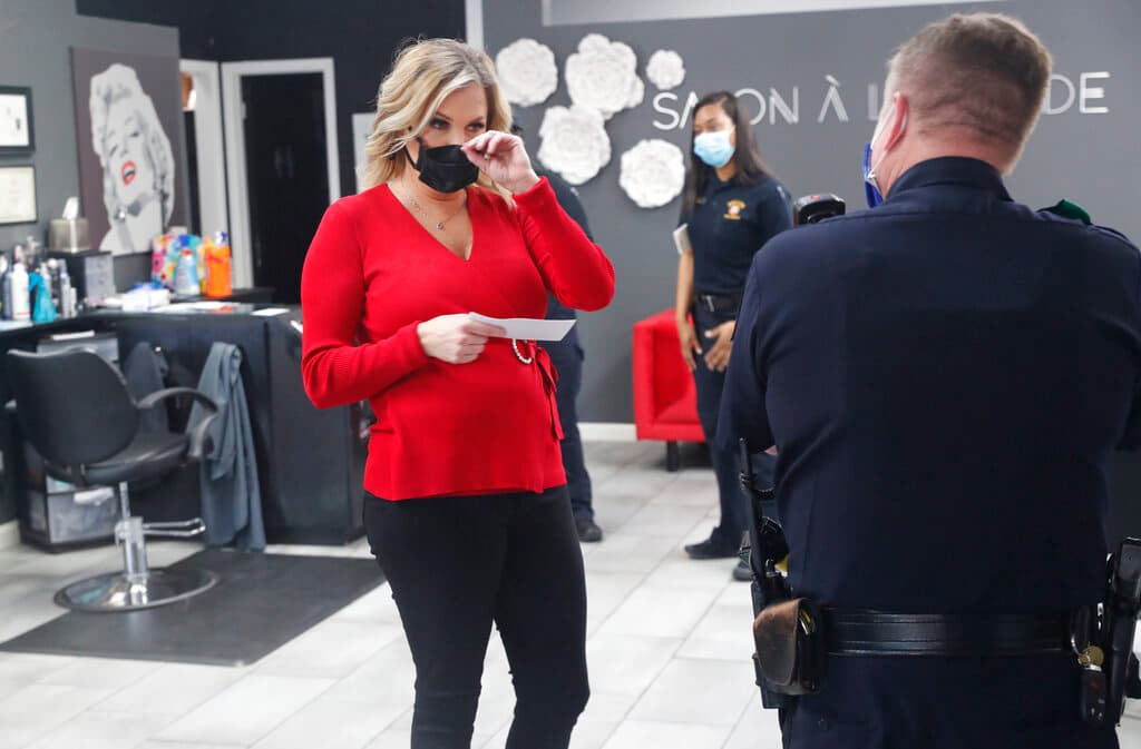 Shelley Luthers, dueña de un salón de belleza, sostiene una citación judicial que le entregó un agente por reabrir su establecimiento a pesar de las restricciones por el coronavirus, en Dallas, Texas.