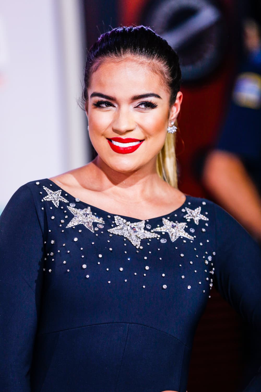 Si quieres imitar el estilo de Karol G la clave está en los labios rojos, usa un labial Mac Ruby Woo y hazte una coleta alta que haga lucir tu cara.