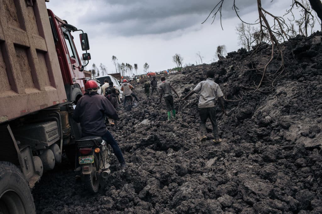 Conductores de motocicletas y camiones
<b>atraviesan el flujo de lava solidificada</b> del volcán Nyiragongo en los vecindarios del norte de Goma, la capital provincial de Kivu del Norte, el 28 de mayo de 2021.