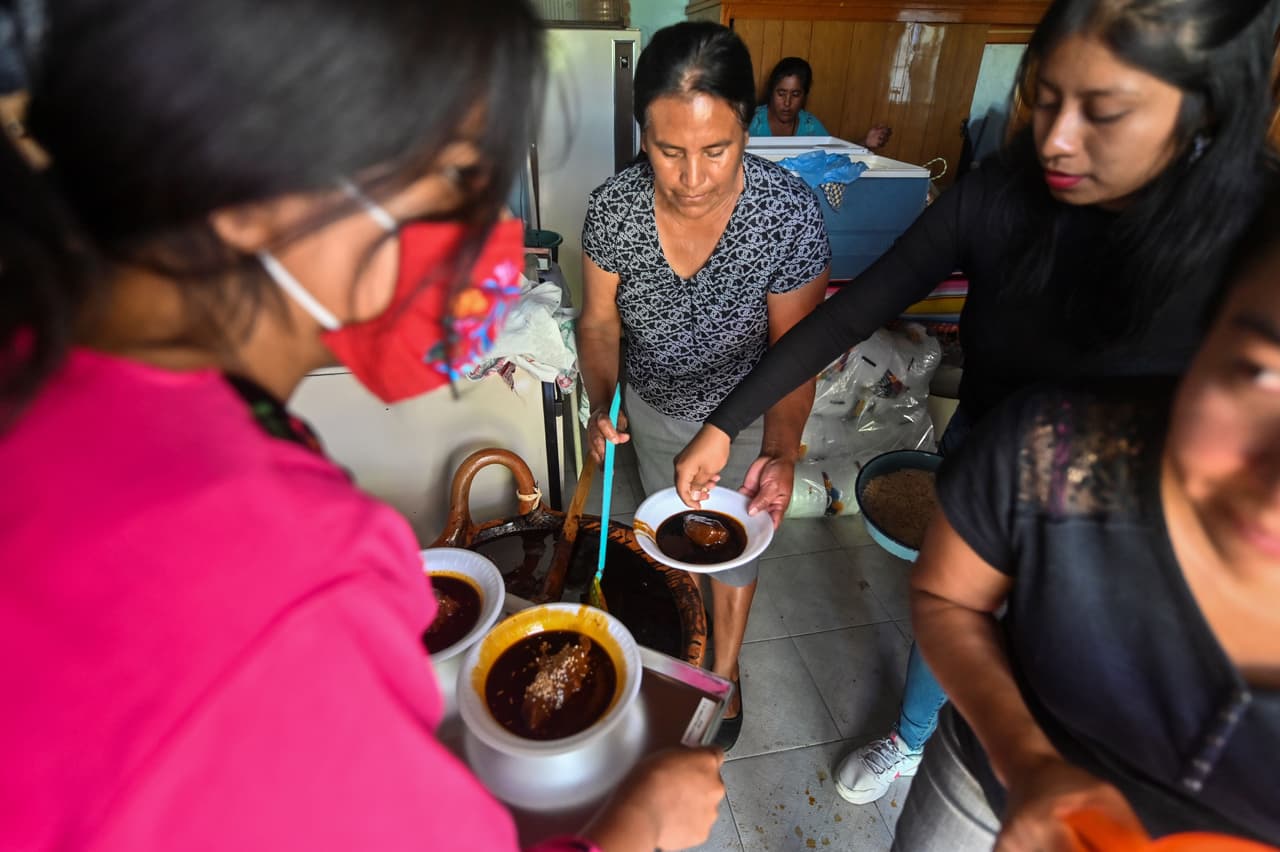 Mujeres preparan mole para las visitas durante un ritual dedicado a su hermano migrante Pablo Vargaz Mendoza de 60 años, quien murió en Nueva York víctima de COVID-19, en Huaquechula, Puebla, México, el 1 de noviembre de 2020, en medio de la pandemia del coronavirus COVID-19.