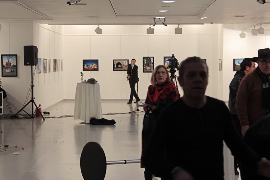 Los asistentes al evento donde fue el atentado se alejan del pistolero que asesinó al embajador.