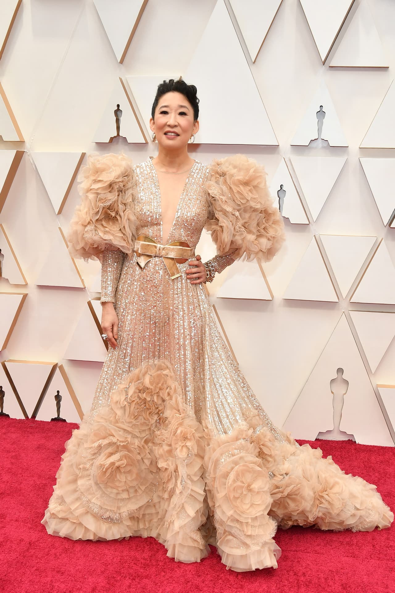 La actriz Sandra Oh utilizó este vestido largo con escote profundo, cinturón y detalles en los brazos.
