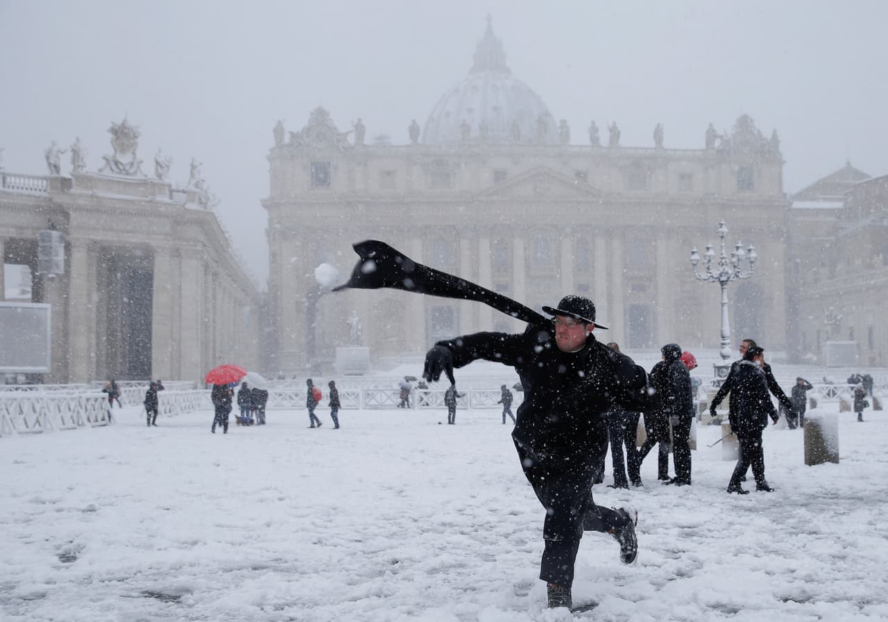 En la Plaza de San Pedro, en Ciudad del Vaticano, este joven sacerdote se divierte lanzando bolas de nieve.