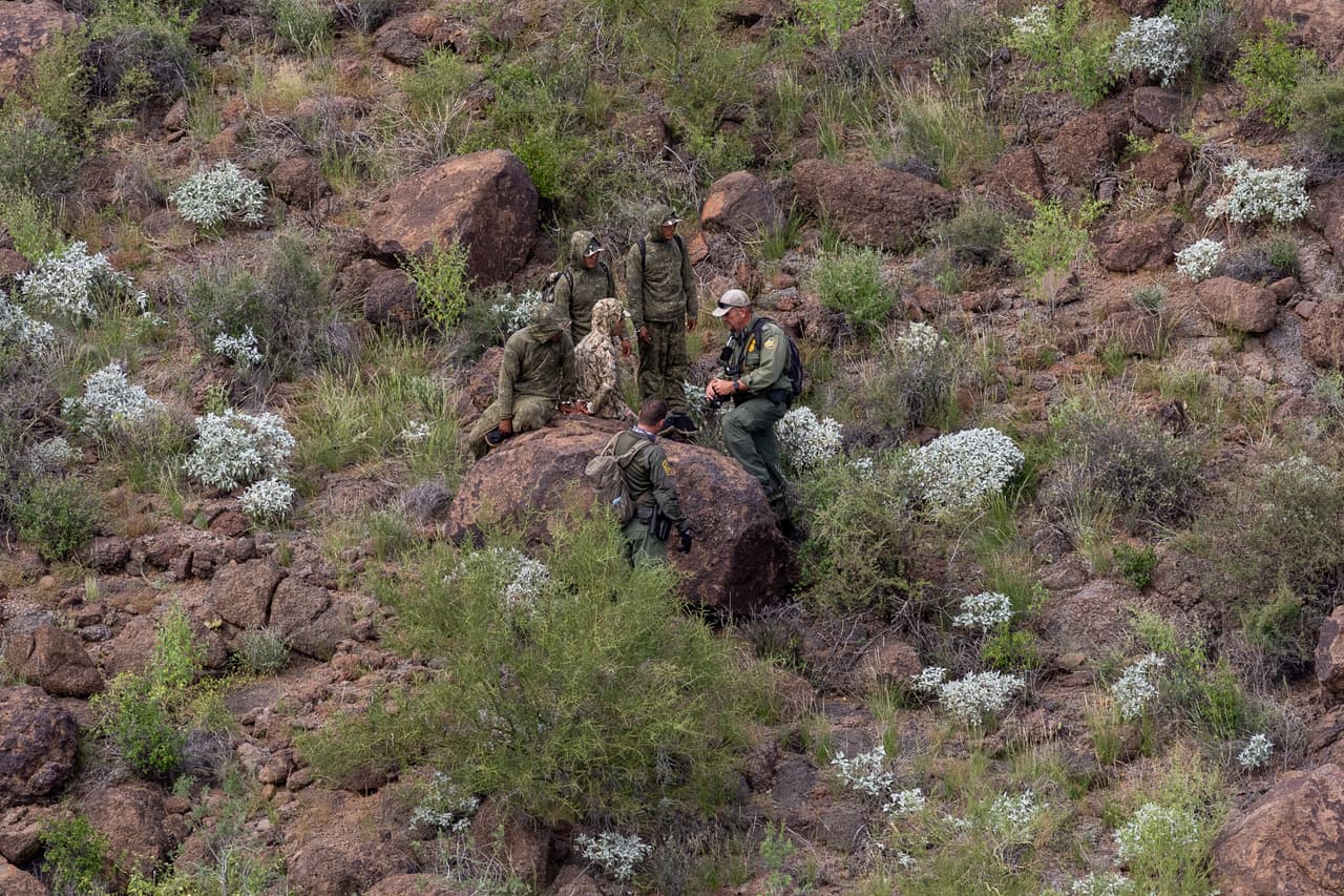 Un agente de la Patrulla Fronteriza habla con inmigrantes esposados después de capturarlos en las montañas cerca de la frontera en el Monumento Nacional Organ Pipe, Arizona.