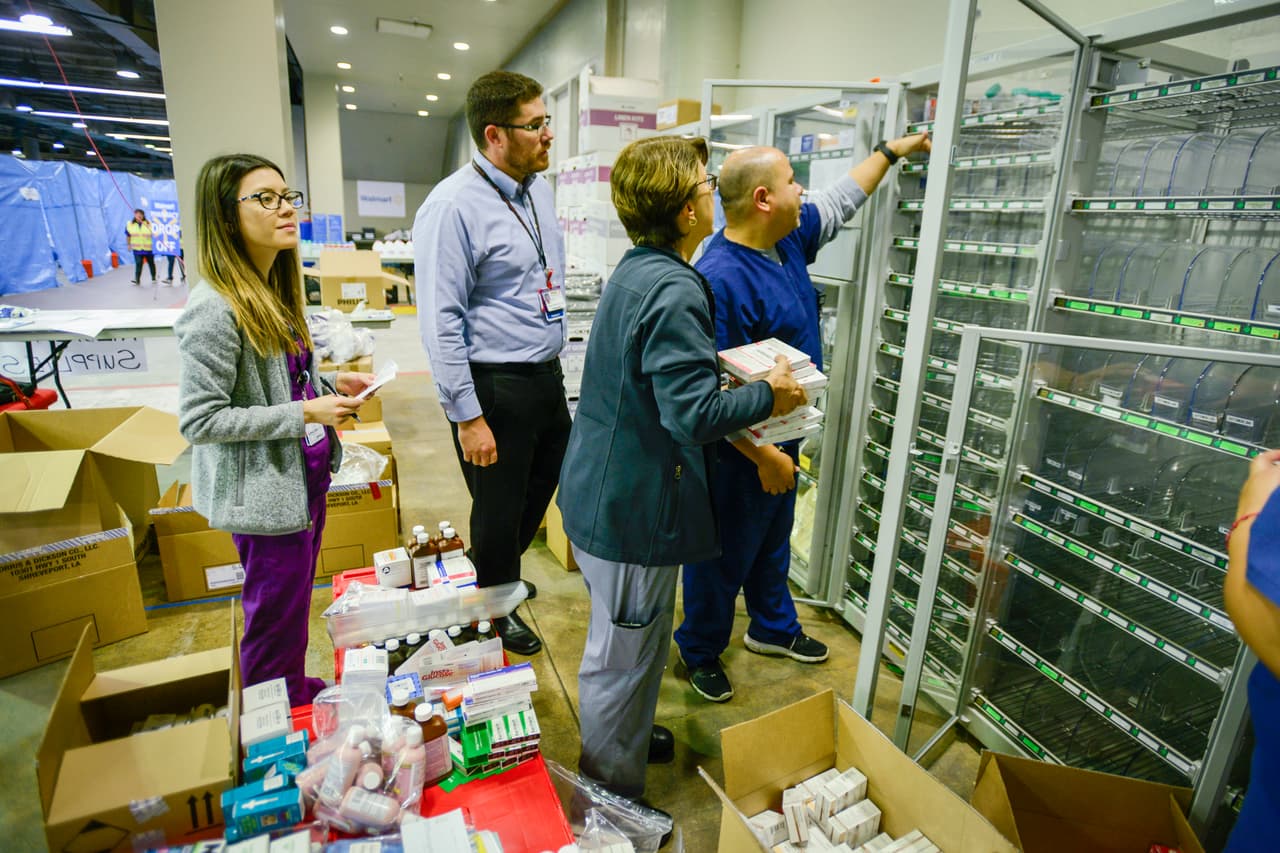 CHST(D170830R): (L-R): Kristine Markham (Pharmacy Resident), Jordan Whitehill (Pharmacy Manager, RPh), Sandra Howell (Pharmacy Manager, RPh), and Raphael Pacheco (Pharmacy Administration) unload, sort, and stock medications and medical supplies into an Omnicell dispensing machine just outside the Pediatric Clinic. Children’s Health Emergency, Virtual Health, Child Life, Pharmacy, and other staff prepare the pediatric clinic in the “Megashelter” located in the Kay Bailey Hutchison Convention Center in downtown Dallas, in anticipation of the arrival of refugees from areas in Southeast Texas affected by Hurricane Harvey.