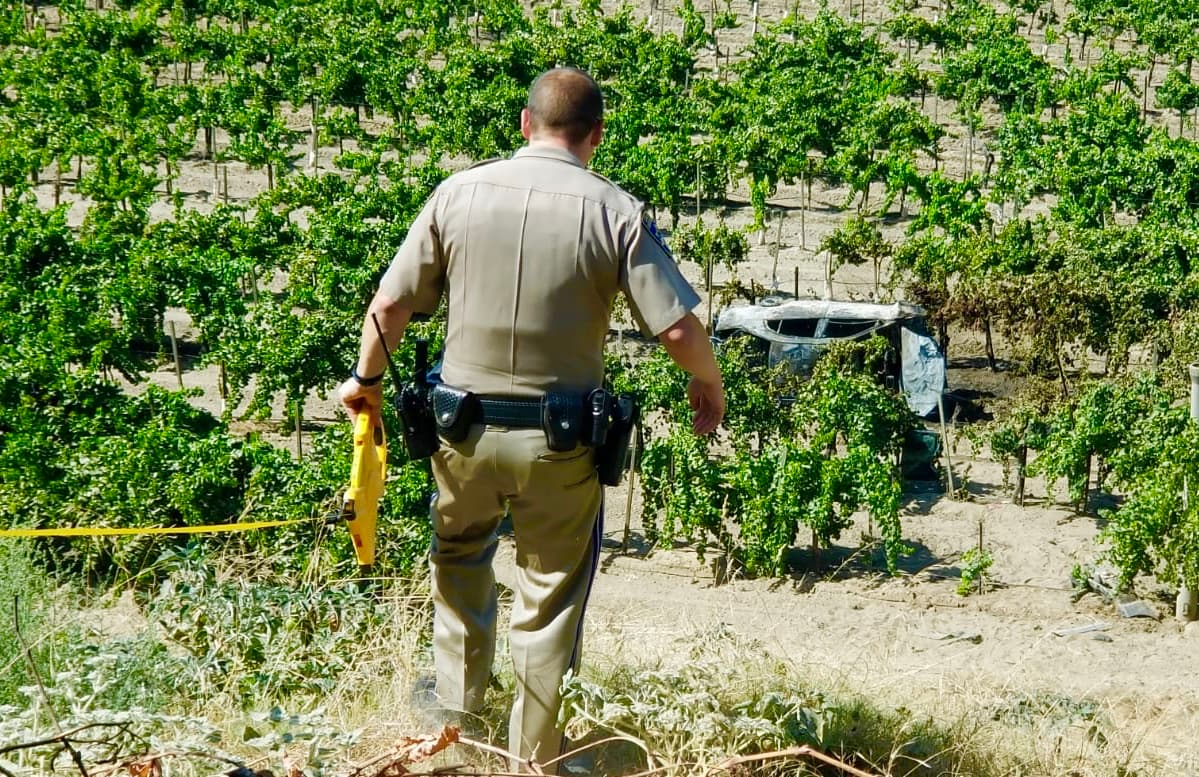 La Patrulla de Caminos de California cerca el lugar donde el automóvil se incendió, en medio de un viñedo en la intersección de la Avenida rolinda con Herndon en Fresno.