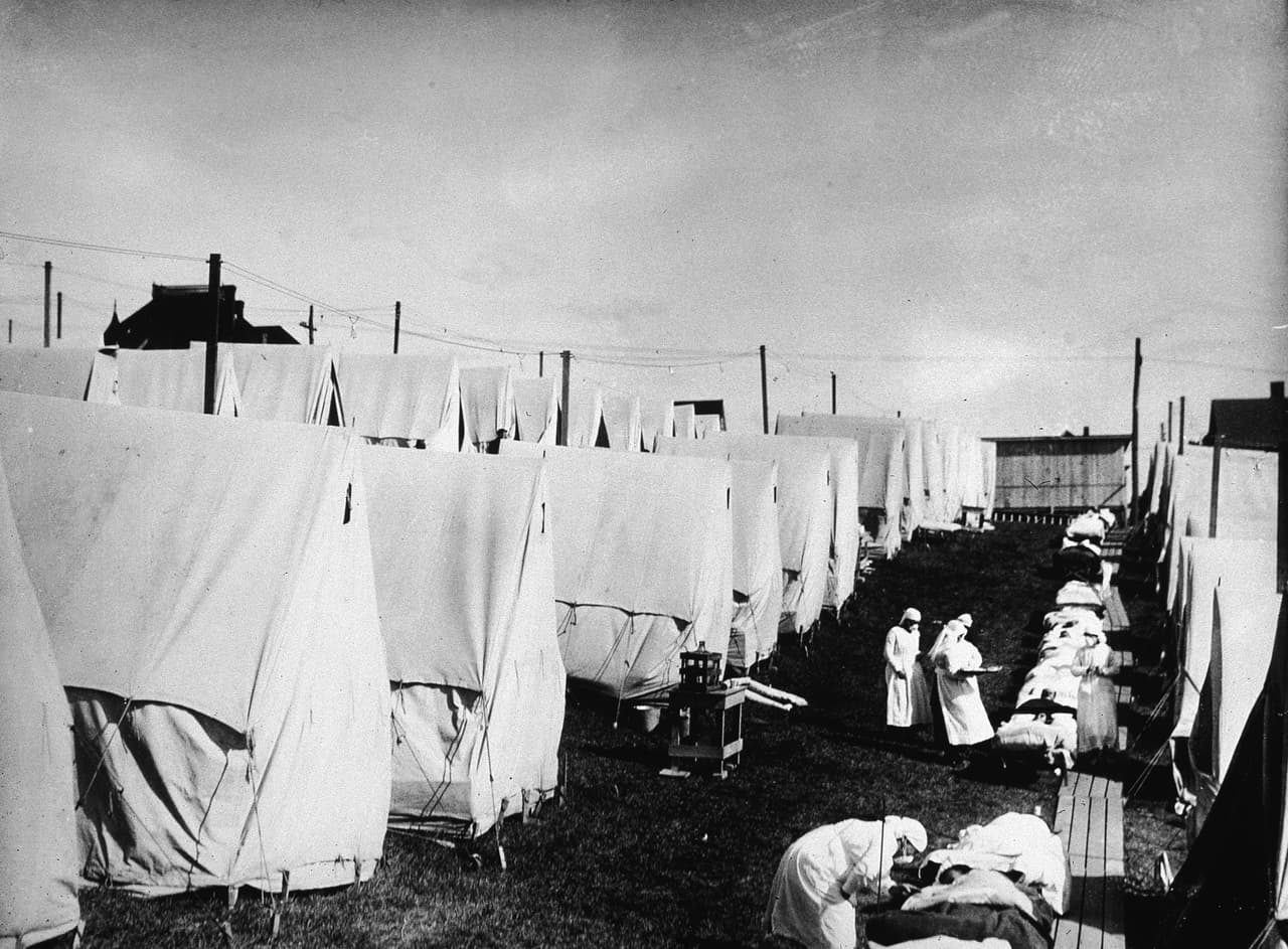 <b>Gripe española de 1918 (1918-1919).</b> Esta influenza del tipo H1N1 afectó Europa y EEUU, dejando alrededor de 50 millones de muertos. Fue uno de los eventos más catastróficos de la historia de la humanidad, pero contribuyó en los avances de la planificación de políticas públicas para evitar la propagación. El resultado de la muerte de tantos hombres por la gripe y la Primera Guerra Mundial impulsaron la incorporación de las mujeres en roles de liderazgo en todo el mundo. En la fotografía, un grupo de enfermeras atienden a los enfermos de gripe española en Lawrence, Massachusetts, 1918.
<br>