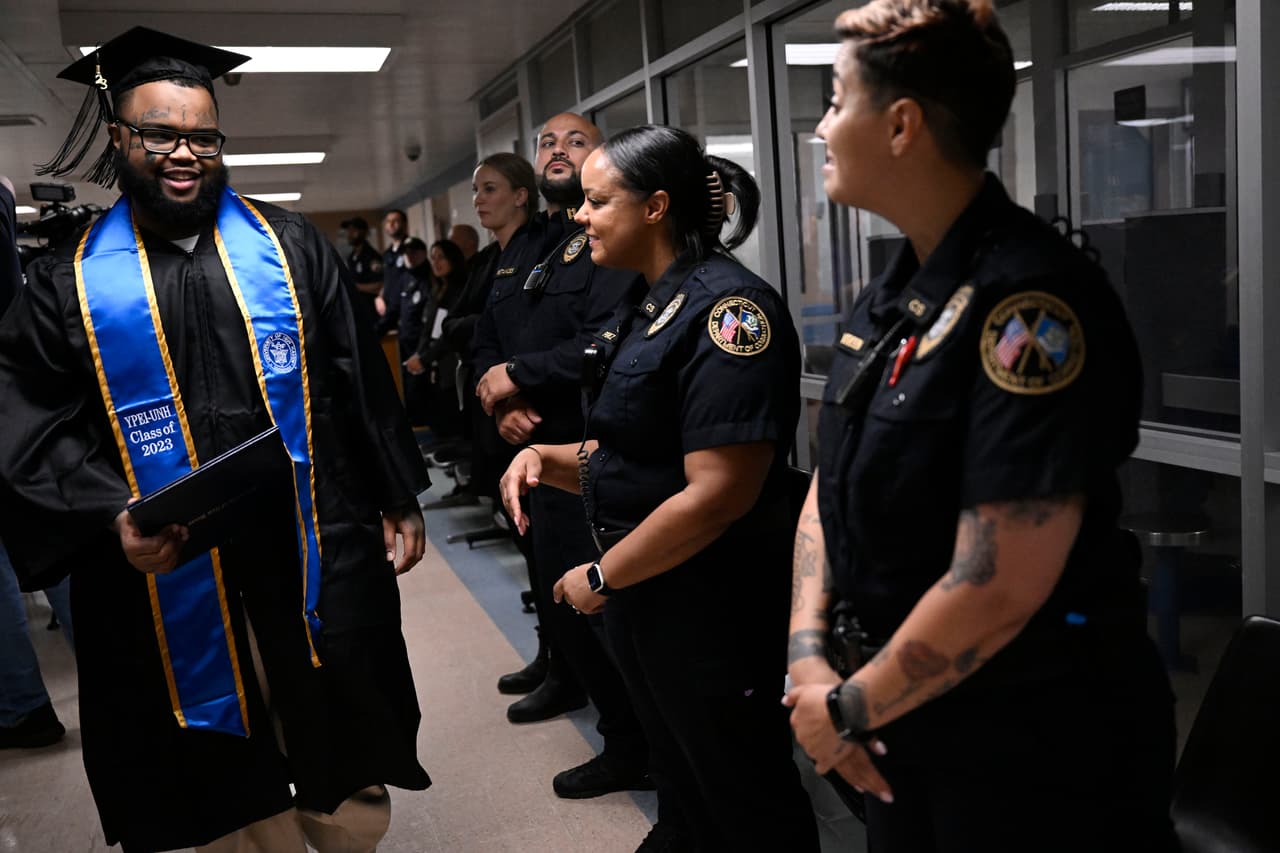El reo Alpha Jalloh camina con su diploma junto a guardias correccionales que lo felicitan en la primera ceremonia de graduación universitaria en la Institución Correccional MacDougall-Walker, el viernes 9 de junio de 2023, en Suffield, Connecticut.