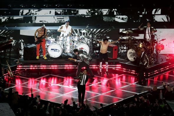 Un cuidado estilismo retro, una banda llena de energía y una particular mezcla de soul y rock sirvieron al cantante Bruno Mars para cautivar a la millonaria audiencia del Super Bowl durante el descanso de la gran cita anual del fútbol americano. Mars, de sólo 28 años y sobre quien planeaba la duda de si sería capaz de enfrentarse a un escenario de tal calibre, optó por un show directo y contundente. Tras una breve introducción a cargo de un coro de niños, un espectacular solo de batería sirvió para abrir el fuego y dar paso rápidamente al gran éxito "Locked Out of Heaven". Impecablemente vestido con una chaqueta dorada, despachó el tema junto a una banda con una amplia sección de viento que se lució en las coreografías. Sin más dilación, Mars descargó su segundo hit, "Treasure", y a continuación demostró su capacidad para fusionar el soul, el pop y el rock integrando en su espectáculo a los Red Hot Chili Peppers. La banda de Anthony Kiedis y Flea puso a saltar a todo el estadio Metlife con su clásico "Give it Away". Los rockeros californianos, a pecho descubierto como manda la tradición, solo necesitaron un par de minutos para demostrar que siguen en buena forma y ceder de nuevo el protagonismo a Mars.