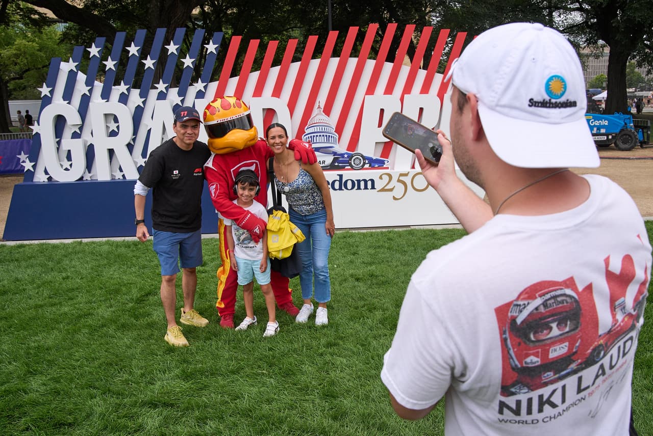 David Avalos, de 7 años, y sus padres, Hector Avalos y Ana Oceguda, de Washington, se toman una foto con la mascota de Firestone Tires durante los eventos previos a la carrera de autos