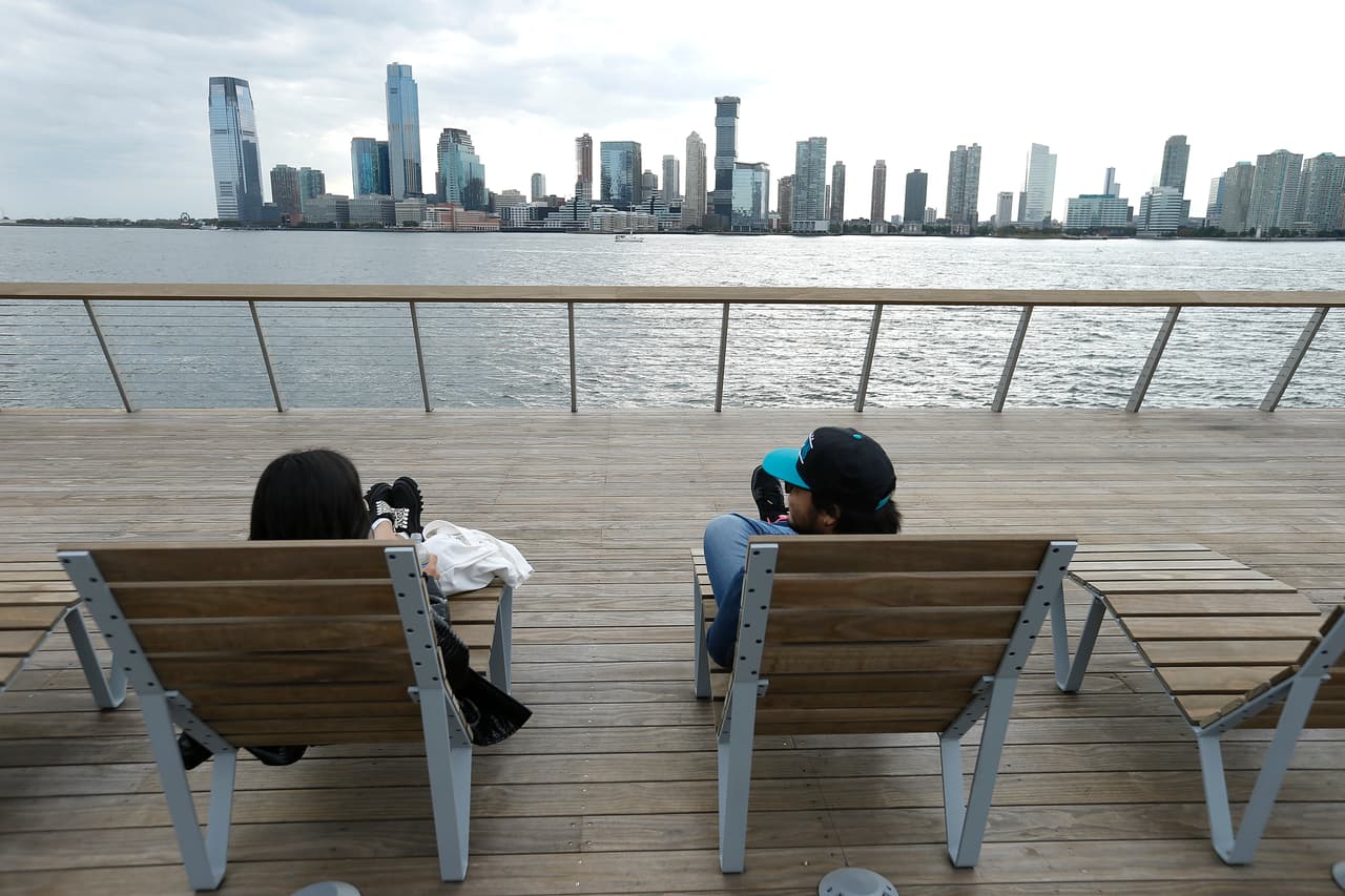 El parque cuenta con césped, una cancha de deportes y cubiertas elevadas sobre el agua.