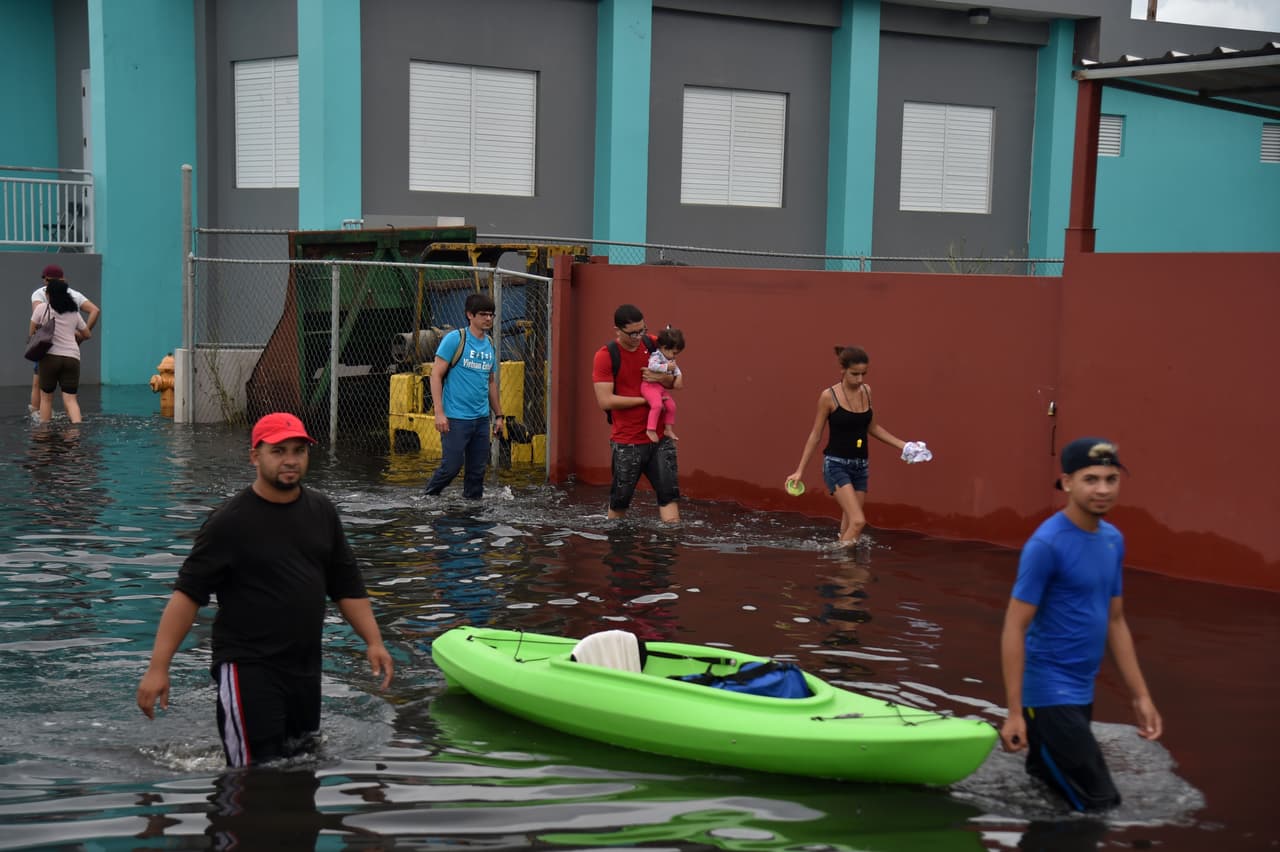 Familias se desplazan por las calles anegadas de Juana Matos, en la capital de la isla.