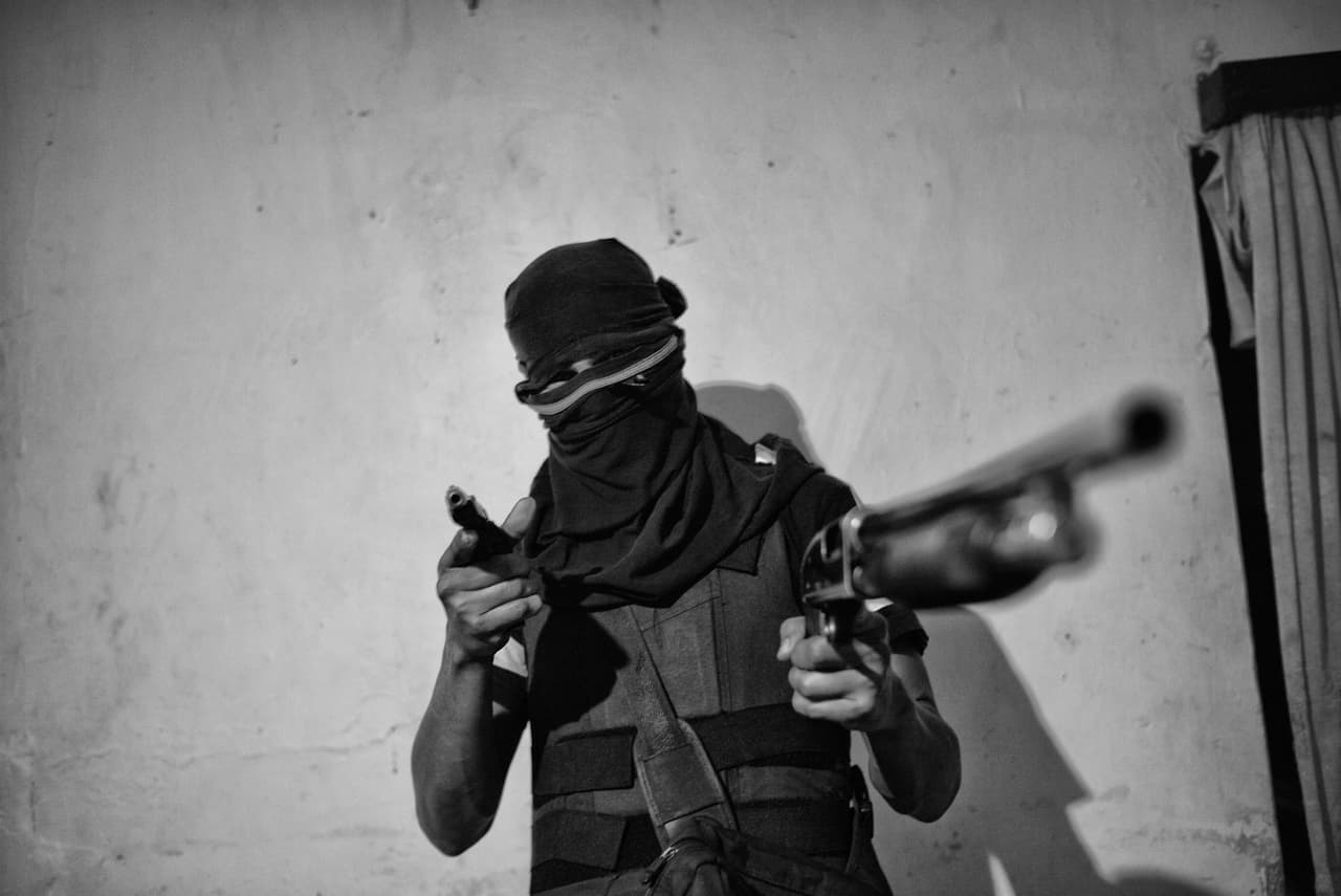 'El Jhonny' juega con su escopeta y apunta al fotógrafo para la foto.