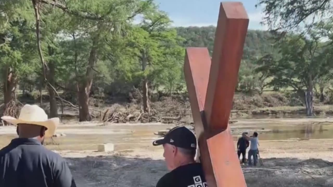 Recordatorio de fe en medio de la tragedia: un hombre lleva una cruz a la orilla del río Guadalupe