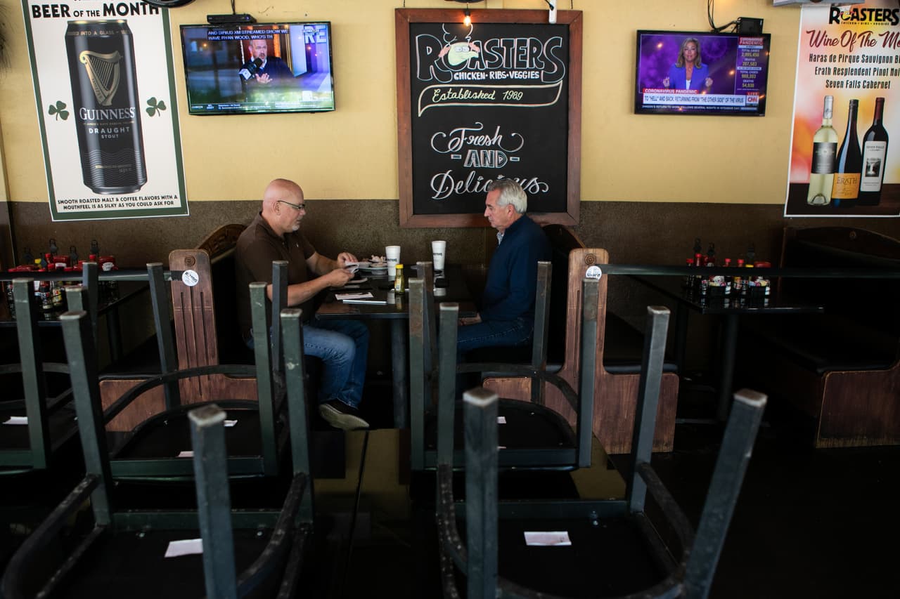 Dan Krisman (izquierda) y Mark Bartlett almuerzan en el patio de Roasters el 27 de abril de 2020 en Atlanta, Georgia. Los comerdores están abiertos con protocolos de distanciamiento social y saneamiento, como limitar la capacidad.