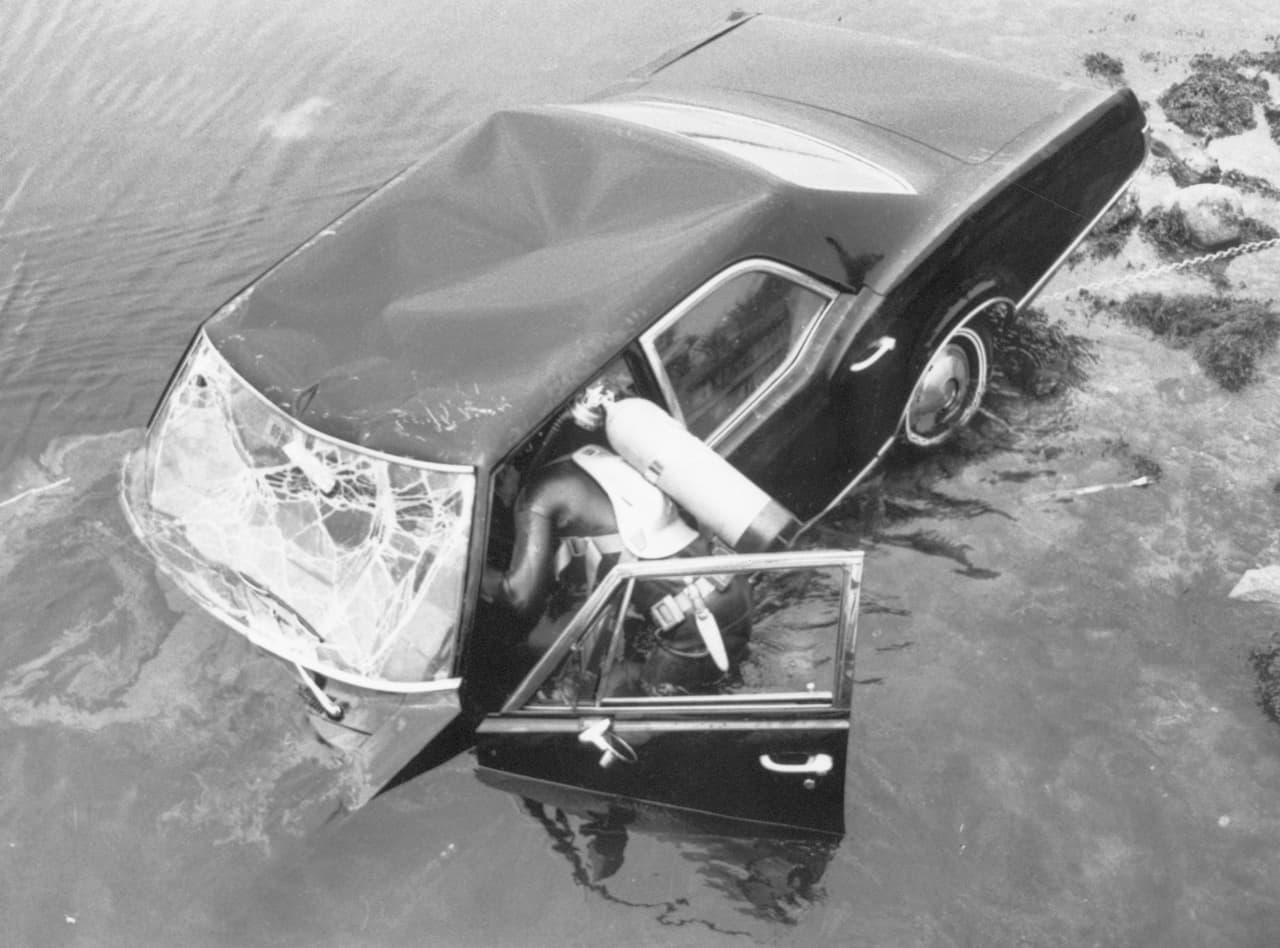 <b>Chappaquidick y la “maldición Kennedy”</b>
<br>
<br>El 18 de julio, el senador Ted Kennedy, patriarca del clan tras el asesinato de sus dos hermanos (John, en 1963 y Robert, en 1968) se vio envuelto en un nunca bien explicado accidente en el que perdió la vida Marie Jo Kopechne, una voluntaria de campaña. Ambos estaban en una reunión en la isla de Chappaquidick, en Massachussetts, con un grupo de colaboradoras de la campaña presidencial de Robert Kennedy. Kennedy y Kopechne dejaron el lugar aunque no está claro si avisaron a los demás de su partida. 
<b>En un punto del camino el auto del senador se salió del estrecho puente por el que circulaba y cayó al riachuelo. Kennedy logró escapar del auto hundido. </b>Según su testimonio intentó varias veces ayudar a la mujer hasta que desistió y regresó caminando al lugar de la fiesta. Allí habló con dos amigos y fueron al sitio del accidente para tratar de rescatar a la joven. Finalmente abandonaron el lugar y sacaron a Kennedy de la isla. Nadie reportó el accidente. Solo a la mañana siguiente un pescador notificó a las autoridades y se logró recuperar el cuerpo de Kopechne. En el juicio en el que Kennedy se declaró culpable de abandonar la escena del accidente y causar daños físicos a un tercero. Fue condenado al mínimo de dos meses de prisión suspendida. Los rescatistas declararon que de haber recibido una notificación inmediata habrían podido salvar a la mujer. 
<b>El 25 de julio, Kennedy ofreció una declaración televisada en la que se preguntó si realmente existía una “maldición” sobre su familia, pese a que la fallecida fue Kopechne. </b>
<br>