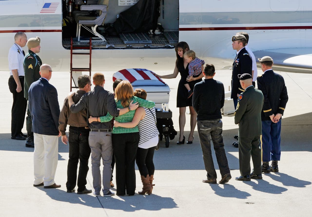 Claudia MacPherson, sosteniendo a su hijo Brayden, toca el ataúd de con los restos de su esposo muerto en combate en Afganistán. La familia recibió en el aeropuerto de Los Alamitos, California al sargento de ejército Thomas R. MacPherson, quien murió en un tiroteo con fuerzas del Talibán el 12 de octubre de 2012.