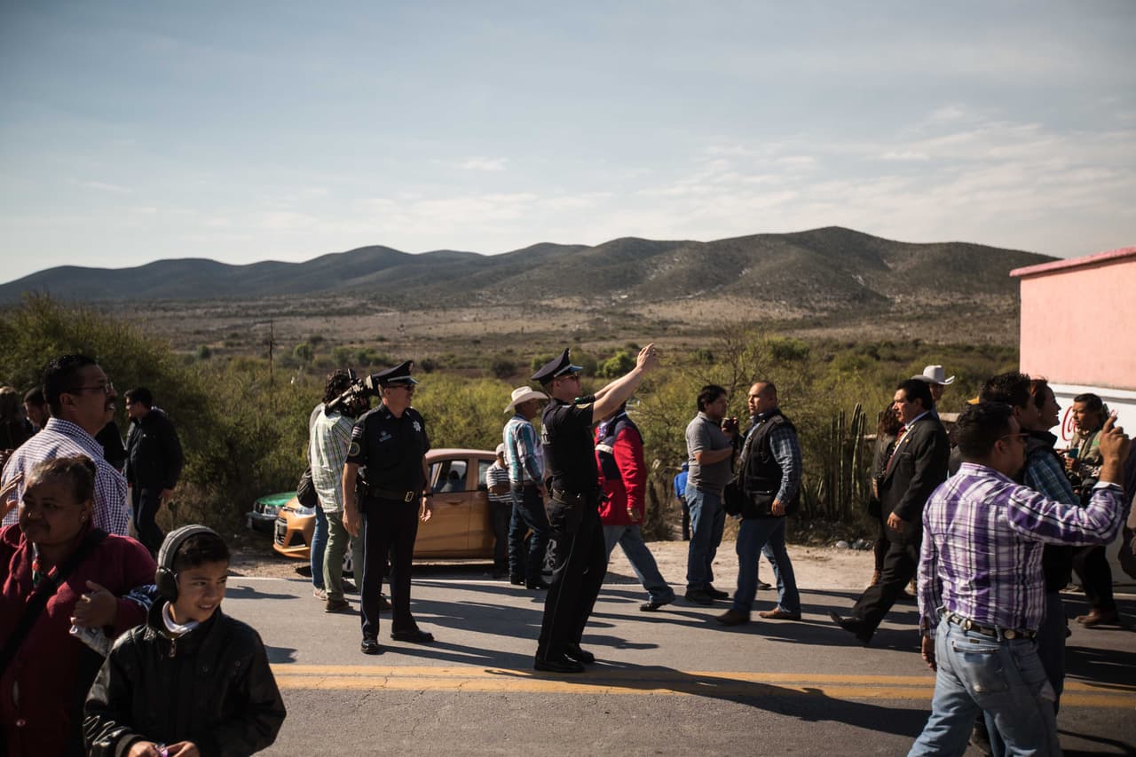 Un policía toma una foto con su celular al carro donde viaja Rubí Ibarra al salir de su casa camino a la misa.