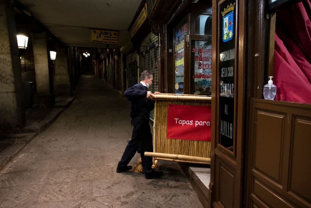 Un empleado de un restaurante en el centro de Madrid guarda una mesa poco antes de las 11:00 pm, cuando empieza el toque de queda en la capital española.