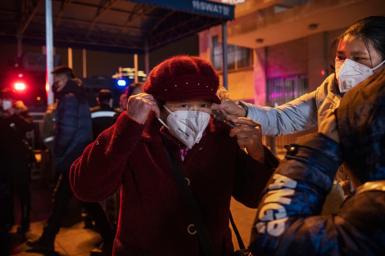 Al principio, las autoridades de China dijeron que no había evidencia de una transmisión de persona a persona en el brote actual, pero un panel de expertos demostró lo contrario. En la fotografía, una mujer recibe ayuda para colocarse una máscara protectora en Beijing, antes de viajar para el festival anual de primavera el 22 de enero de 2020.
<br>