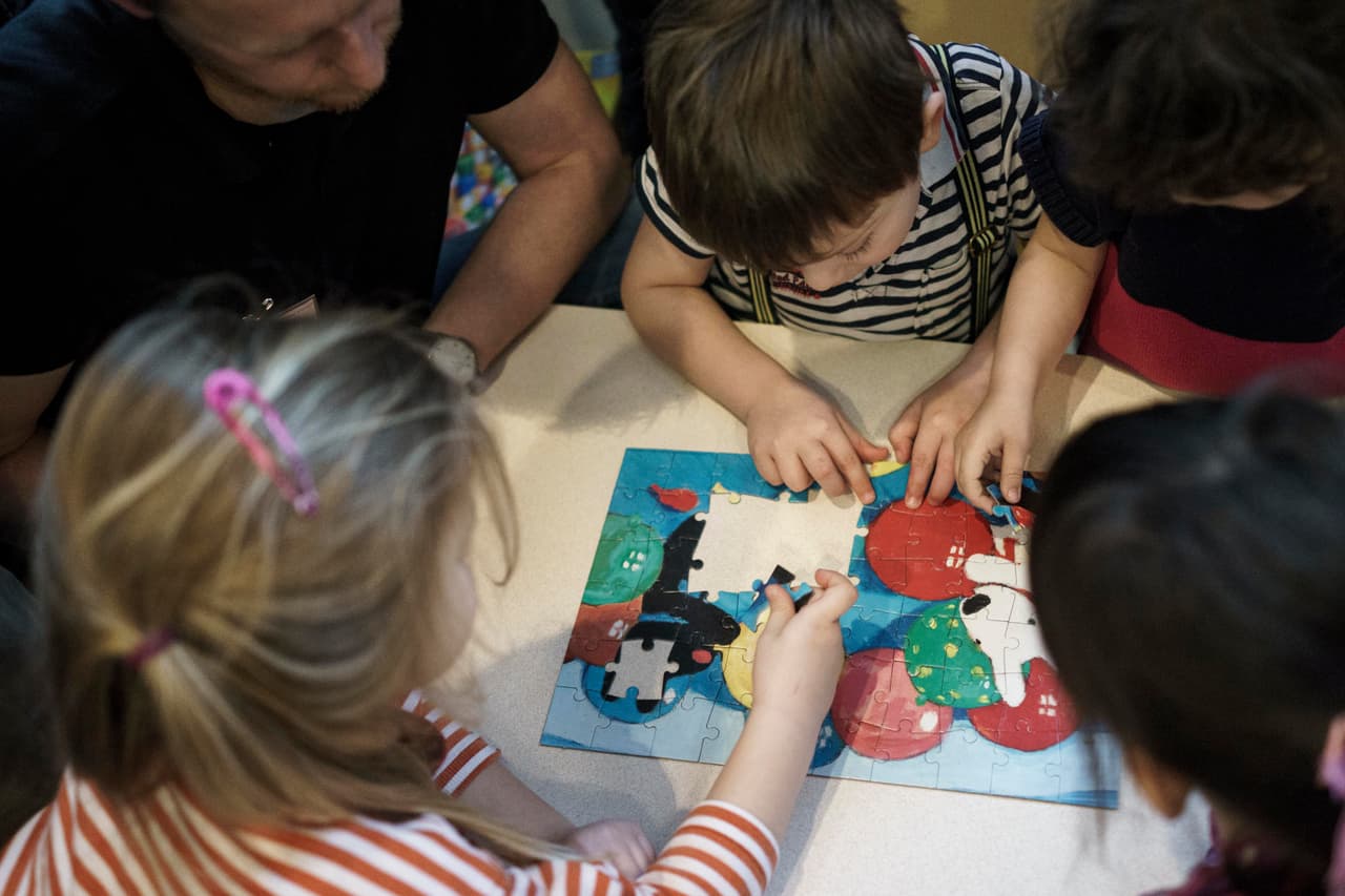 BERLIN, GERMANY - JANUARY 12: A childminder plays helps children with a puzzle as German Family Minister Manuela Schwesig and Minister of Work and Social Issues Andrea Nahles visit the Juwo Kita child day care center in Friedrichshain district on January 12, 2015 in Berlin, Germany. The Juwo Kita is among day care centers that will participate in the new KitaPlus initiative by the German government that will allow child day care centers to open for longer hours throughout the day, enabling greater flexibility for the children's working parents. (Photo by Carsten Koall/Getty Images)