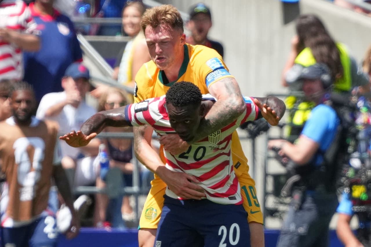 Harry Souttar (19) de Australia sujeta a Folarin Balogun (20) de Estados Unidos durante el partido de fútbol del Grupo D de la Copa Mundial entre Estados Unidos y Australia en Seattle, el viernes 19 de junio de 2026.