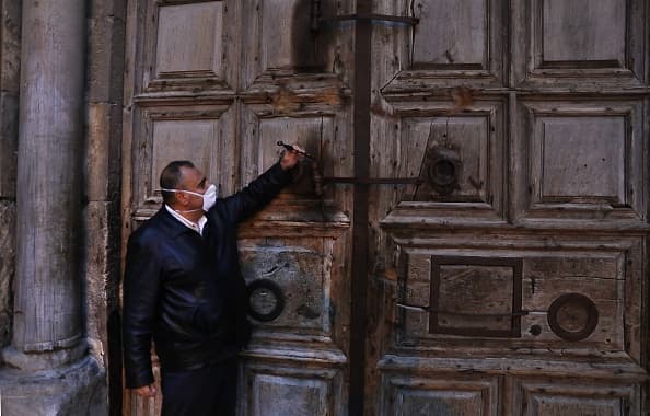 Adeeb Joude, el custodio a cargo de la antigua llave de la Iglesia del Santo Sepulcro, cierra la puerta de entrada a la iglesia debido a la pandemia de coronavirus este 25 de marzo de 2020.
