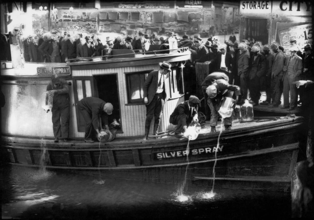 Agentes del gobierno vacían grandes botellas de ron en el río Elizabeth en Norfolk, Virgina, en 1922, en pleno imperio de la Ley Seca en EEUU. (Charles S. Borjes/The Virginian-Pilot via AP)