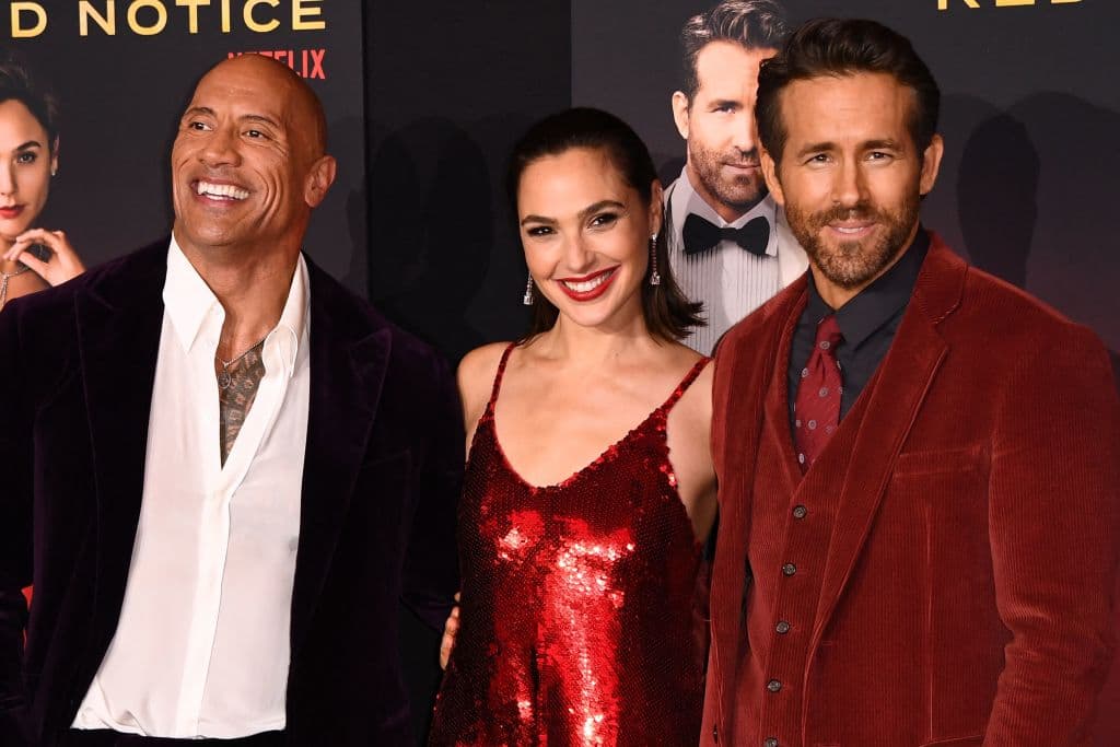 US actor Dwayne Johnson (L), Israeli actress Gal Gadot (C) and Canadian actor Ryan Reynolds attend the world premiere of Netflix's "Red Notice" at LA Live in Los Angeles on November 3, 2021. (Photo by Patrick T. FALLON / AFP) (Photo by PATRICK T. FALLON/AFP via Getty Images)