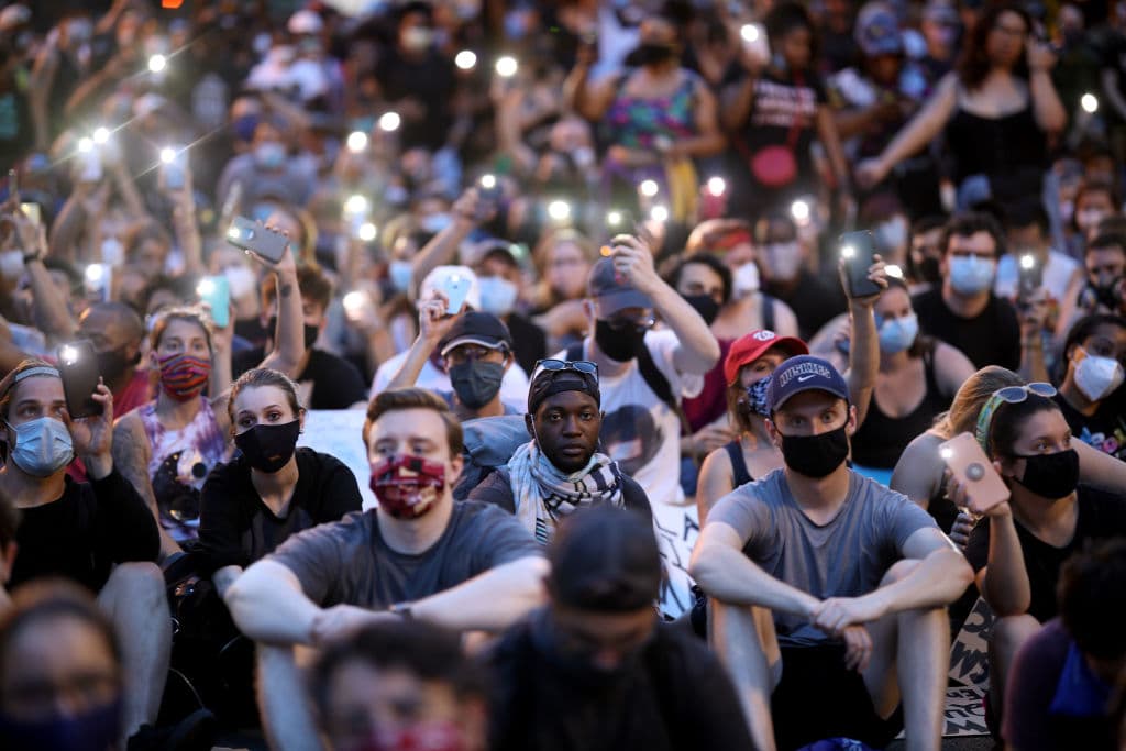 Manifestantes sentados frente a la Casa Blanca. En un momento todos cantaron el tema 'Lean on me'.