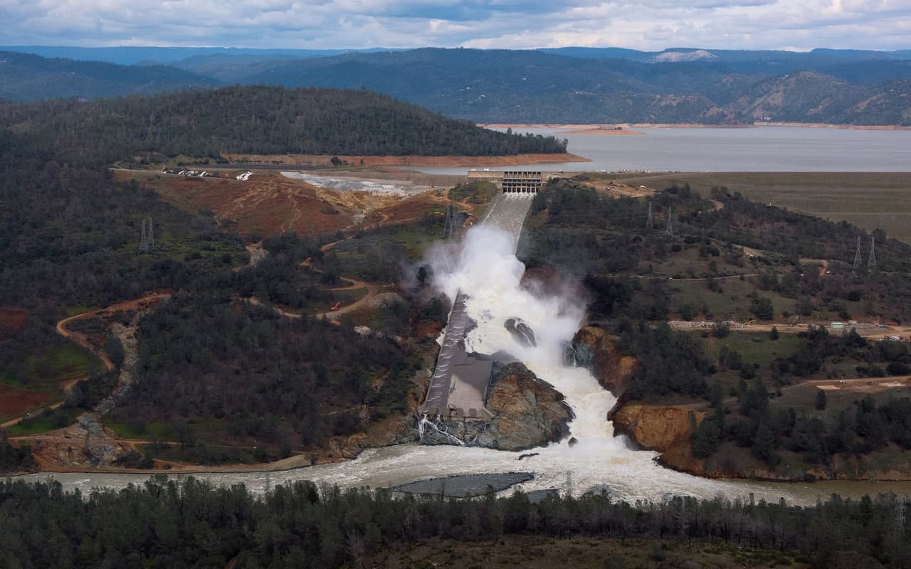 Imagen aérea de la represa Oroville antes del cierre de las compuertas de la rampa principal el 27 de febrero. A la izquierda de la imagen se observa un terreno marrón, junto a la parte superior de la represa. Esa es la zona por la que desagüó cuando rebasó su límite de capacidad. Allí también se observa una gran erosión del suelo.