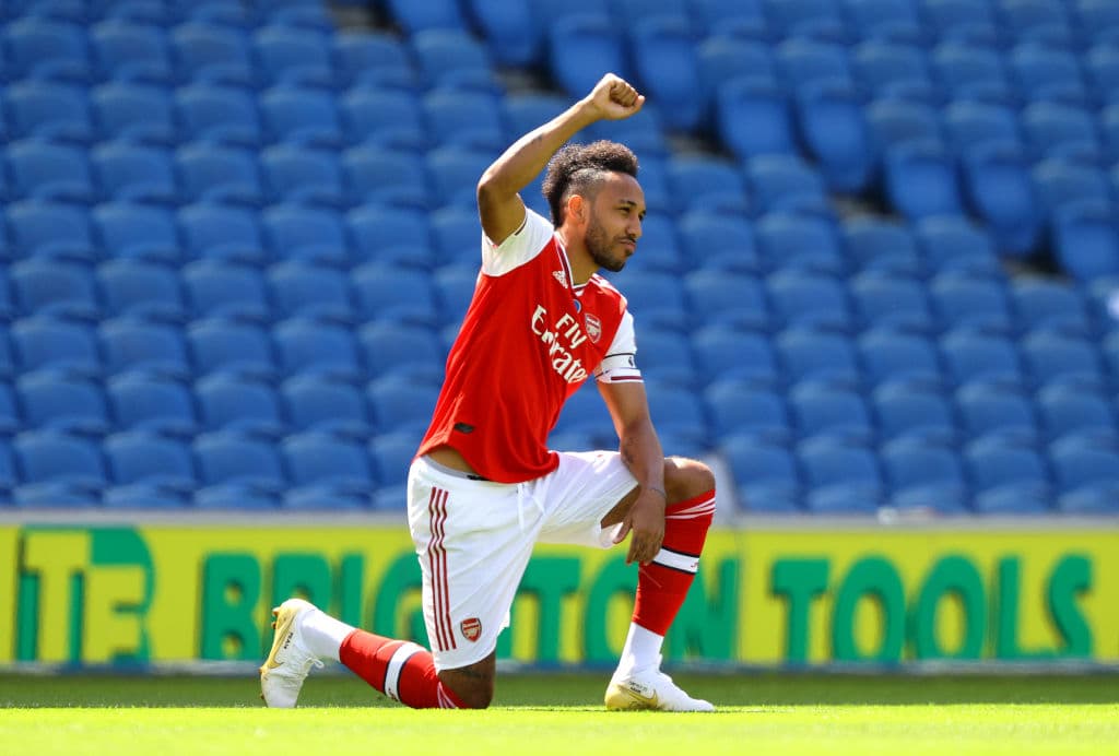 Emerick-Pierre Aubameyang levanta el puño con la rodilla en el césped.