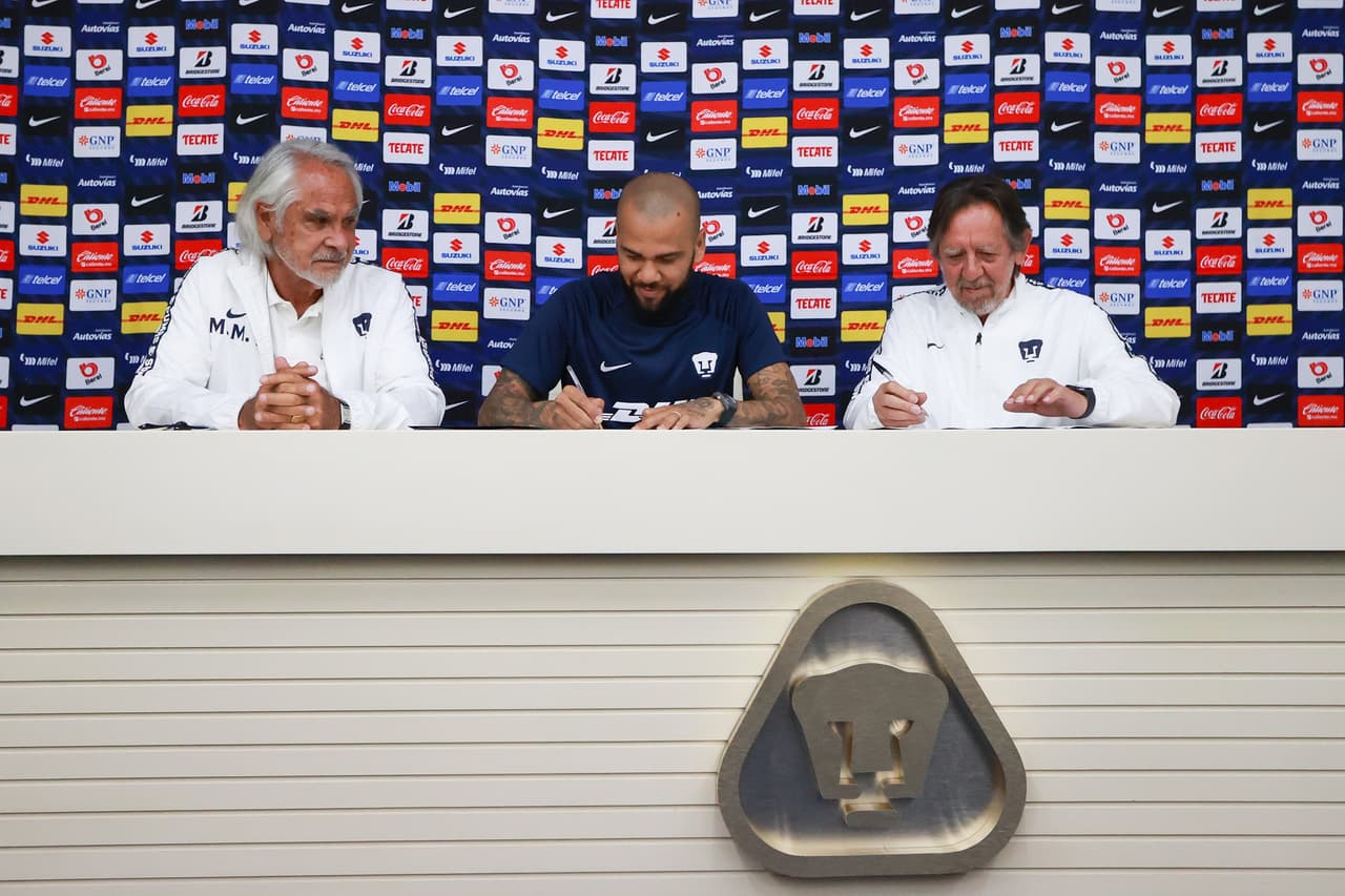 Dani Alves firmando su contrato de un año con Pumas junto al ingeniero Leopoldo Silva, presidente de la junta directiva, y Miguel Mejía Barón, vicepresidente deportivo.