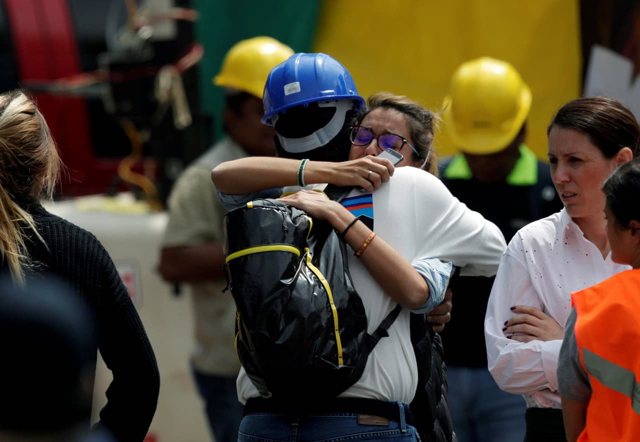 Una persona que tiene un familiar atrapado entre los escombros abraza a uno de los socorristas.