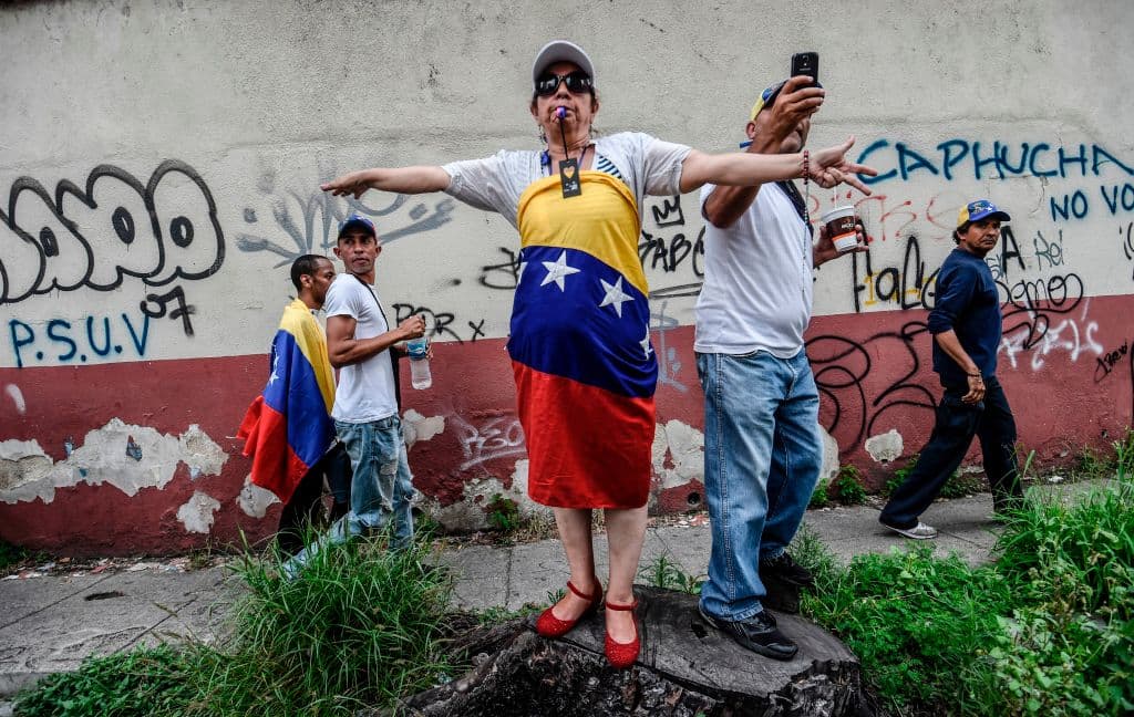 Las banderas de Venezuela siempre están presentes en las manifestaciones contra el gobierno de Maduro. Mientras marchaban, los opositores rompían el silencio al cantar el himno nacional, con rezos o con gritos de "libertad". (Juan Barreto/AFP/GettyImages)