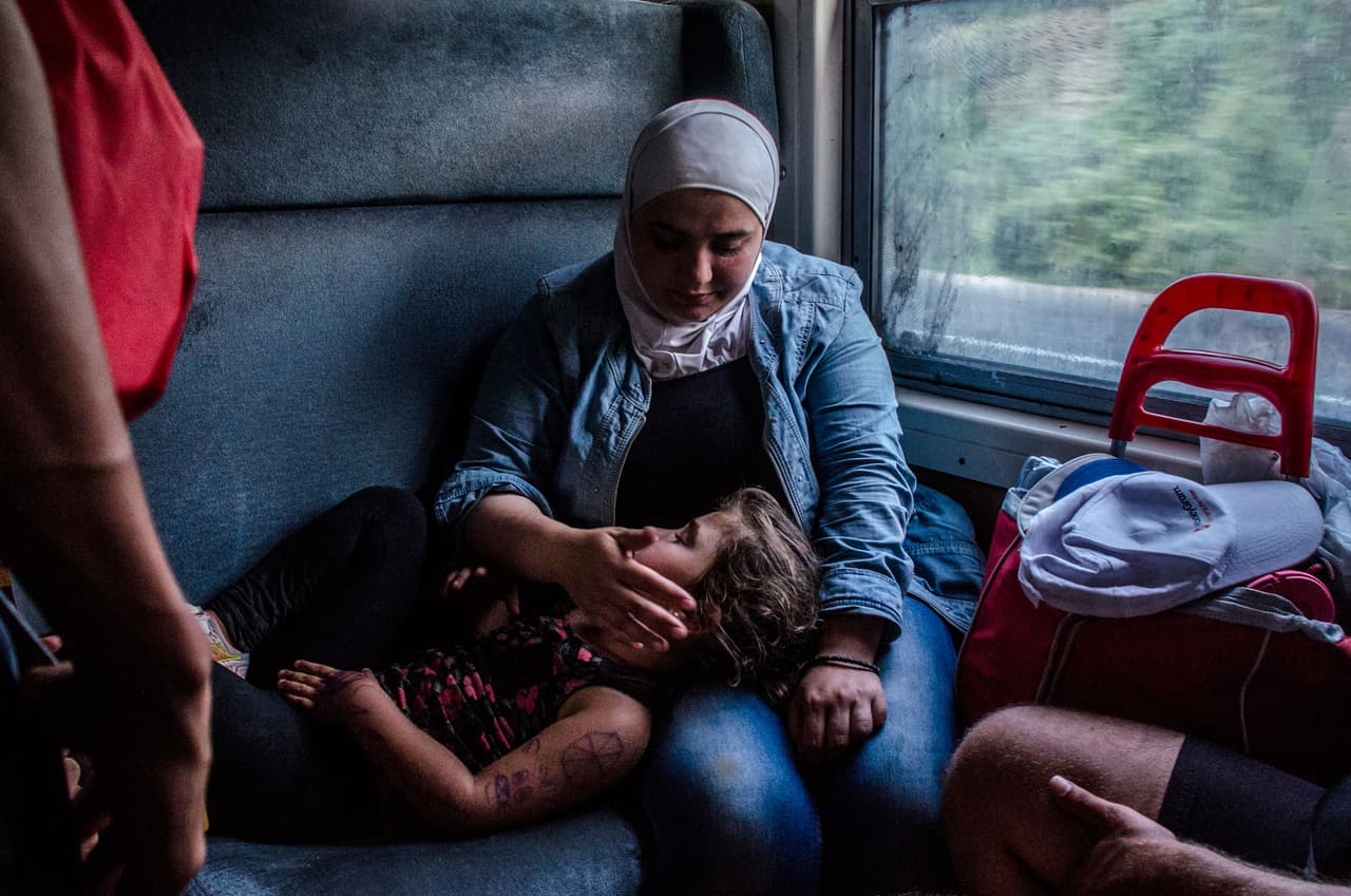<b>Capítulo 4. En las vías del Oriente Express.</b> Dentro del tren es casi imposible moverse. Las familias se acomodan unas sobre otras como pueden. No falta espacio para sonreír, contar historias, jugar cartas, hablar de fútbol o simplemente pensar. Finalmente, los grupos se dividen por la forma de continuar la travesía a través de Serbia. Algunos prefieren caminar a pesar de las amenazas de bandidos. Los más cautos caminan por el campo apartado hacia la frontera. En esta zona remota es ahora es la policía Serbia quien les detiene el paso. Más permisos y esperas para poder llegar a Hungría, la ansiada puerta de la Comunidad Europea. Cuenta Javier Bauluz en su crónica que “el viaje continúa entre el miedo a ser asaltados y la esperanza de cruzar la última frontera”
<a href="http://huelladigital.univisionnoticias.com/crisis-refugiados-javier-bauluz/capitulo-4/"> <b>(VER ESPECIAL COMPLETO).</b></a>
<br>