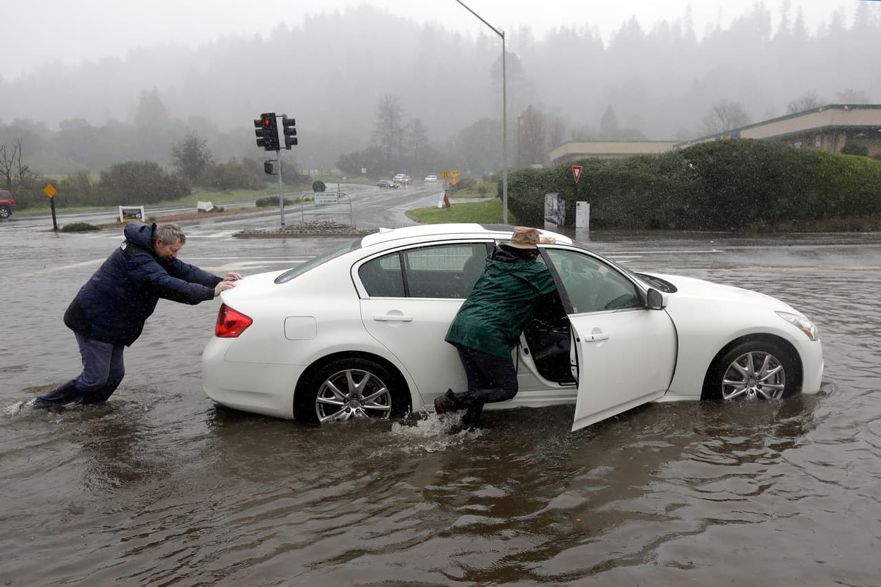 Esta pareja en Felton se vio obligada a empujar su automóvil por una calle inundada.