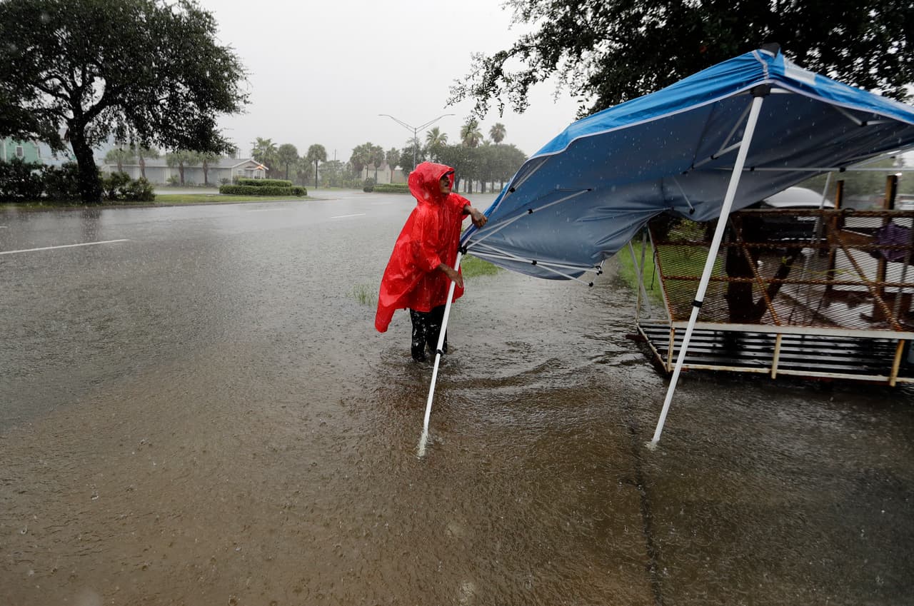 Jesús Escavado baja un toldo en su vecindario en Galveston para evitar que sea arrastrado por las lluvias incesantes que cayeron el miércoles y que este jueves siguen azotando el este del estado.