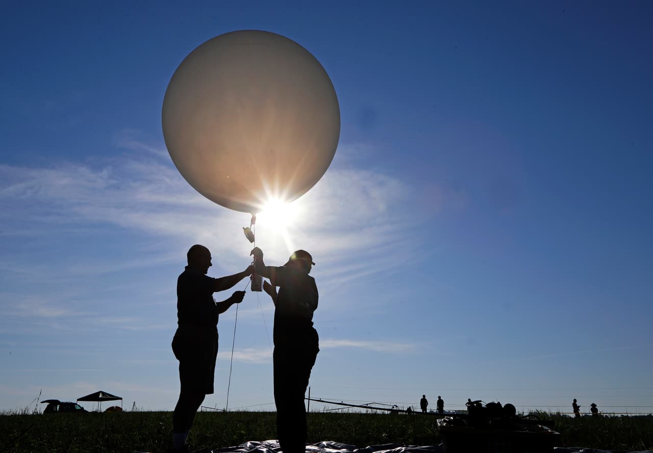 Mike Newchurch, profesor de química atmosférica en la Universidad de Alabama en Huntsville, y la estudiante Paula Tucker preparan un globo meteorológico antes de lanzarlo para realizar investigaciones durante el eclipse solar, cerca de Hopkinsville, Kentucky. La ubicación, que está en el camino donde el fenómeno será total, también está en el punto de mayor intensidad.