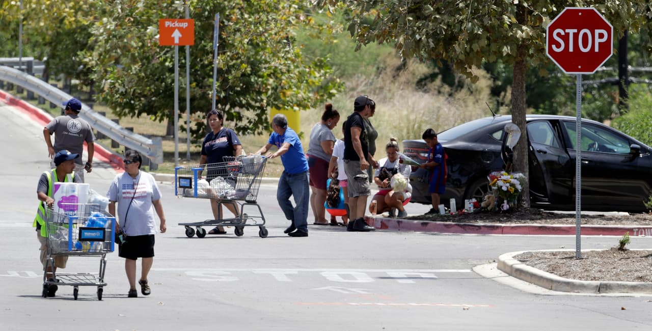 Algunos compradores de Walmart pasan junto a un pequeño monumento a las víctimas del camión, un día después del hallazgo.